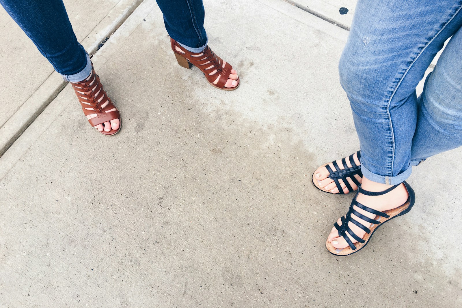 two woman wearing black and brown strappy sandals