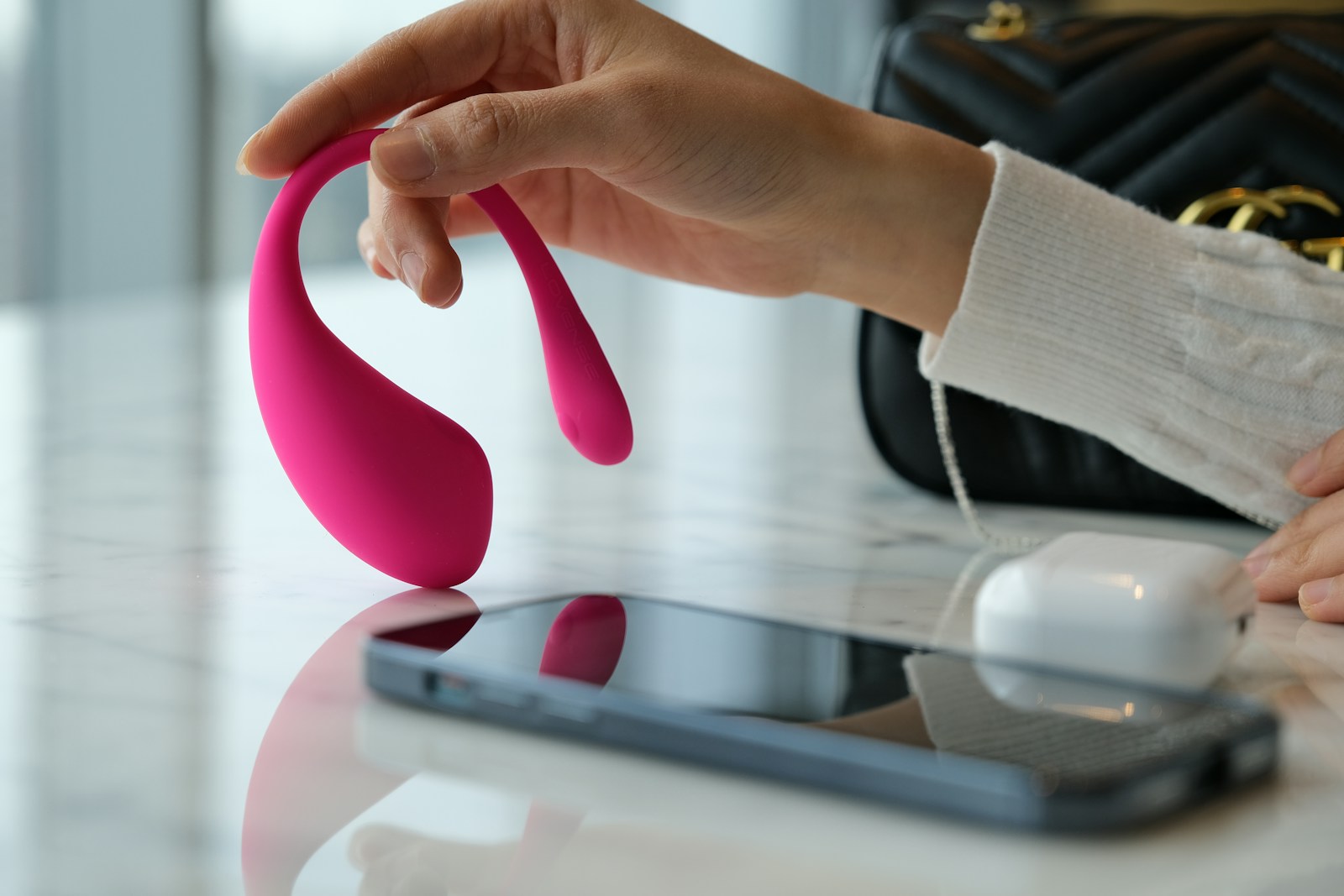 a person holding a pink object near a cell phone